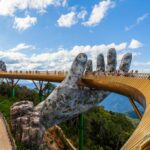 Tourists on Vietnam's Ba Na Hills Golden Bridge being supported by a giant sculpture hand