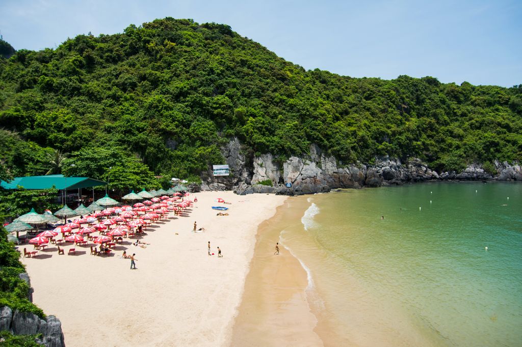 Cat Co 1 Beach in Cat Ba, Vietnam with clean sand, clean water, a few people, and tables and chairs.