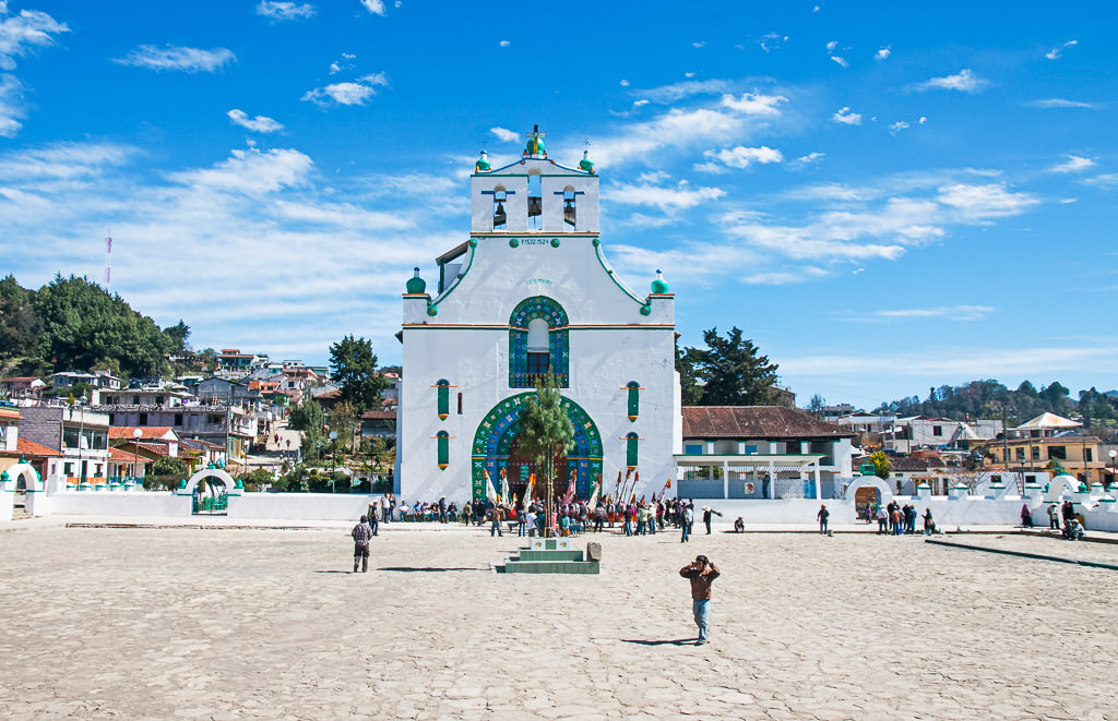 A plaza with people in San Juan Chamula and a church surrounded by residential area in the background.