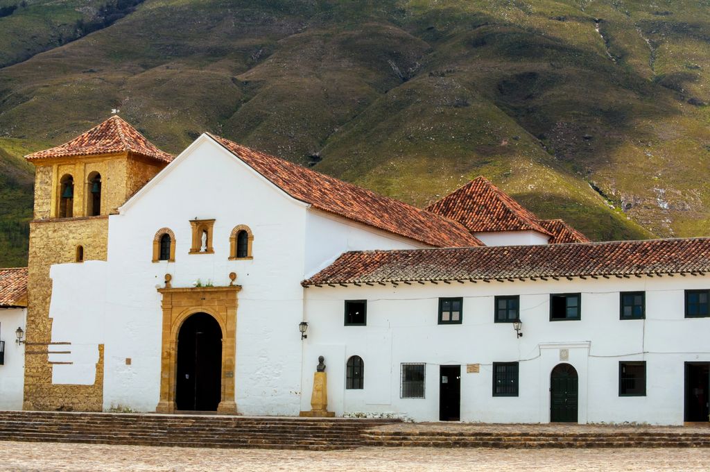 A white church building in Colombia with mountains in the background.