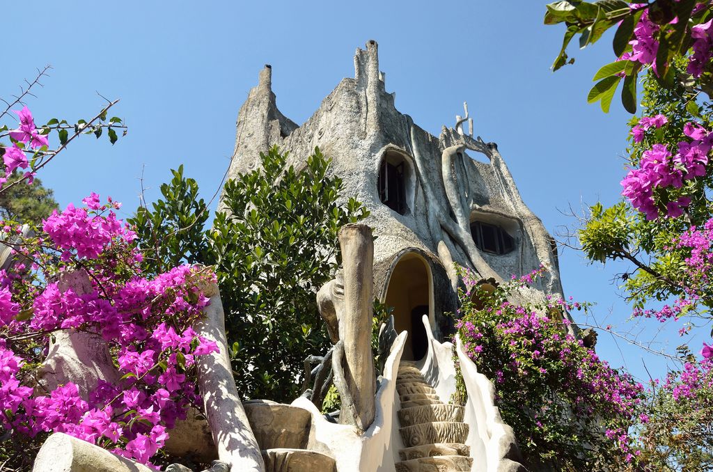 An unusually built building surrounded by flowering plants and tress in Dalat, Vietnam.