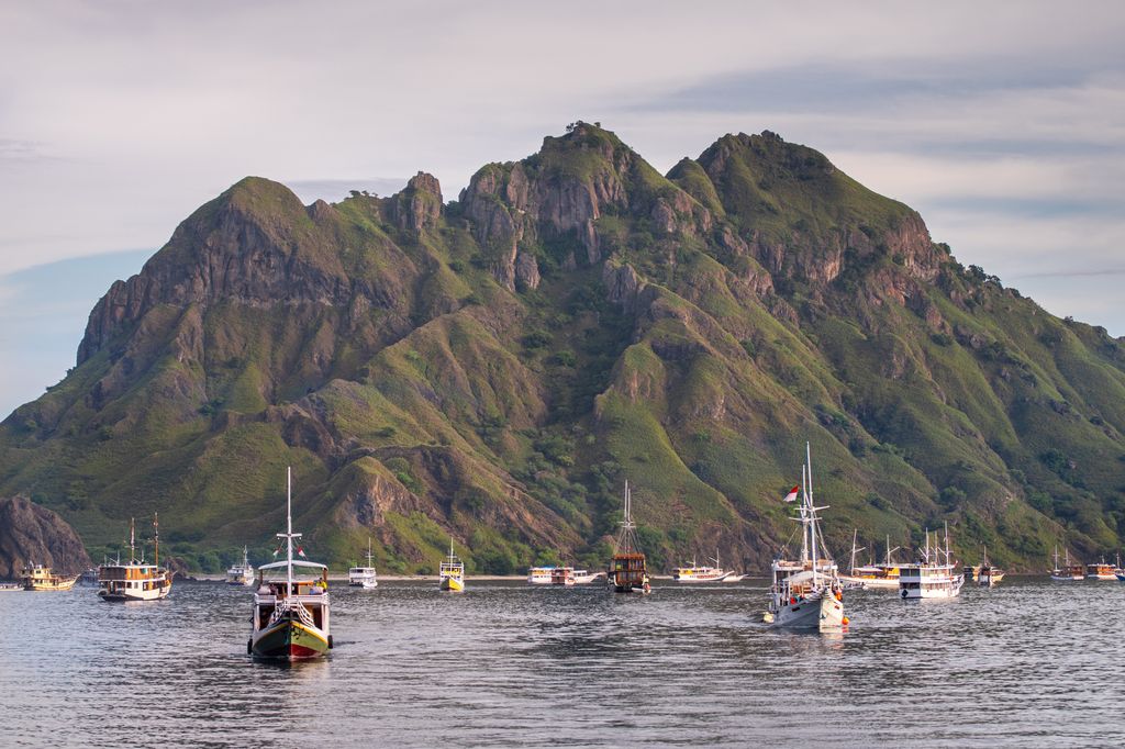 Boats on water and in front of an island in Flores, Indonesia.