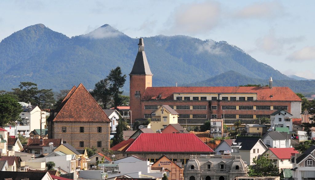 The buildings of Dalat City, Vietnam with misty mountains in the background.