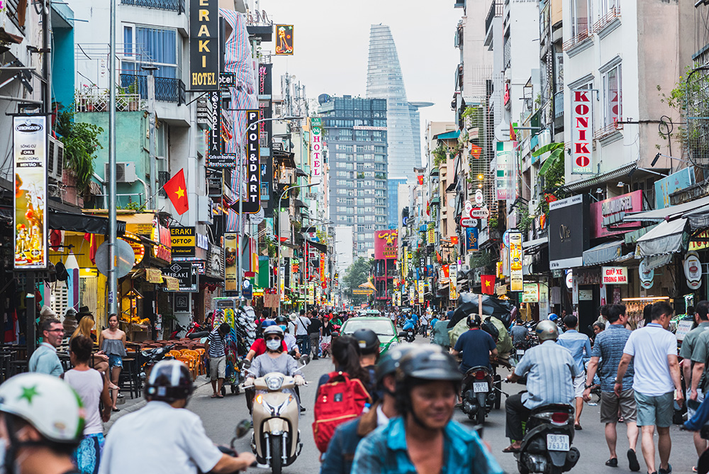 People riding motorcycles on a busy street in Ho Chi Minh City.