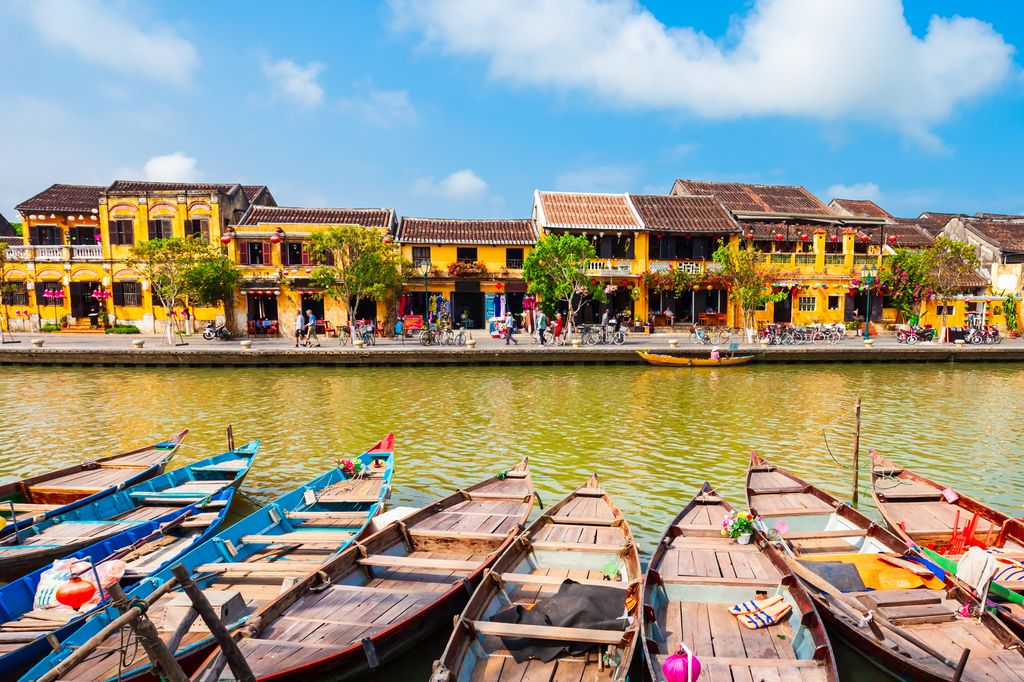 Fishing boats on a river and yellow buildings in the background in Hoi An, Vietnam