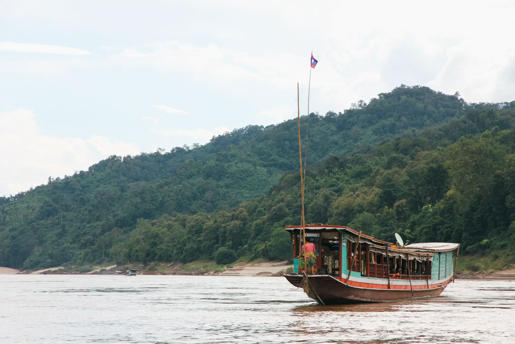 A boat in Laos with hills in the background.