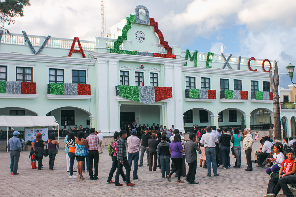 People outside a building in Comitán with green, red, and white decorations.
