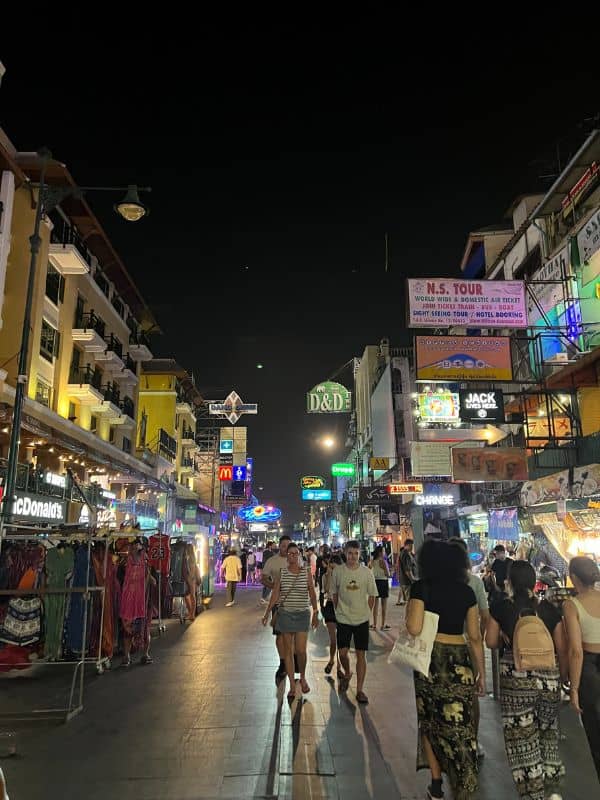People walking on a road in Bangkok, Thailand at night.