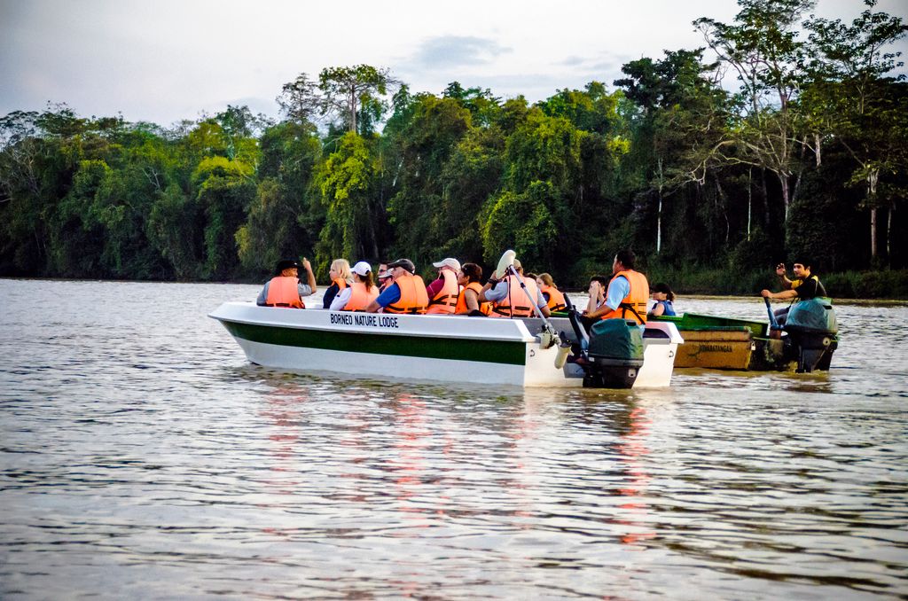 People in life vests riding a boat on Kinabatangan River, Malaysia.