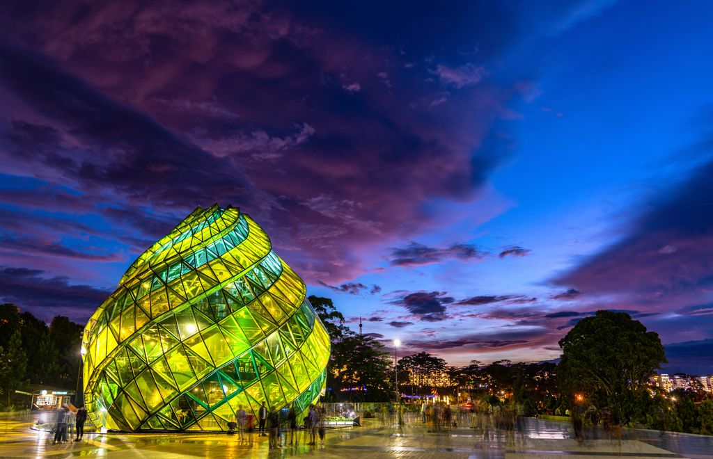 A green dome-like glass structure at a park under the blue and purple sky in Dalat, Vietnam.