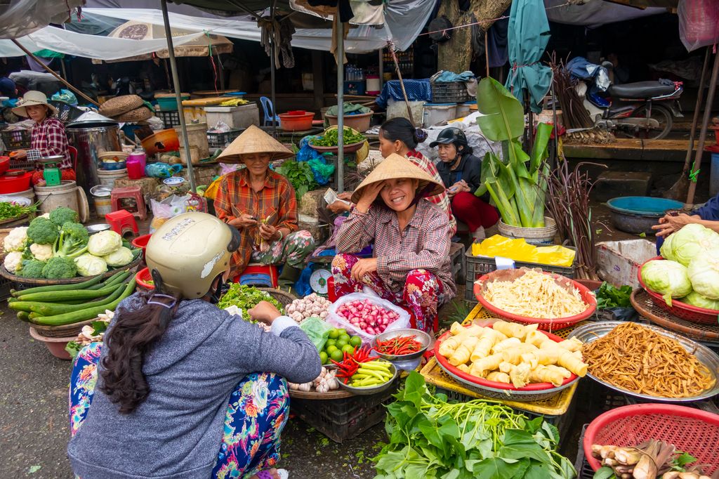 Women selling and buying vegetables at a traditional market in Hue, Vietnam.