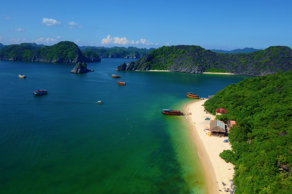 Monkey Island Beach and bay in Cat Ba, Vietnam with boats in greenish-blue waters.