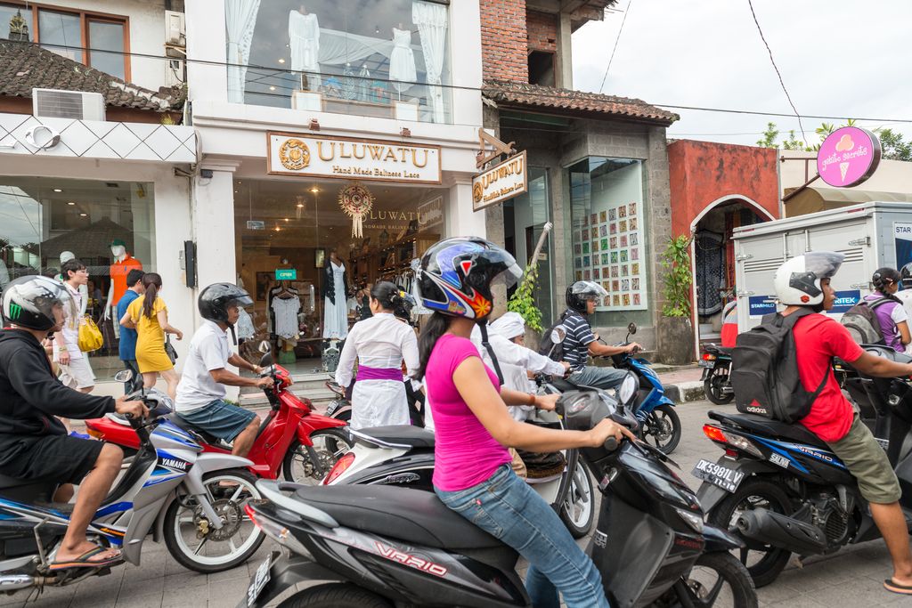 People riding motorbikes on a road in Ubud, Bali, Indonesia.