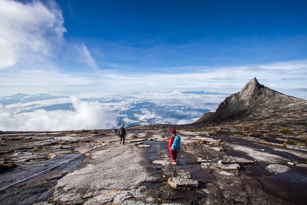 Two people standing on Mount Kinabalu, Malaysia above a sea of clouds.