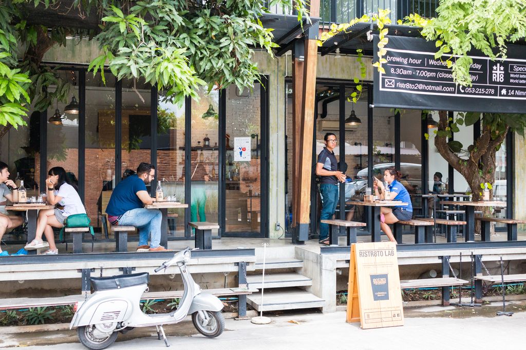 People sitting and standing outside a coffee shop in Nimman, Chiang Mai, Thailand.
