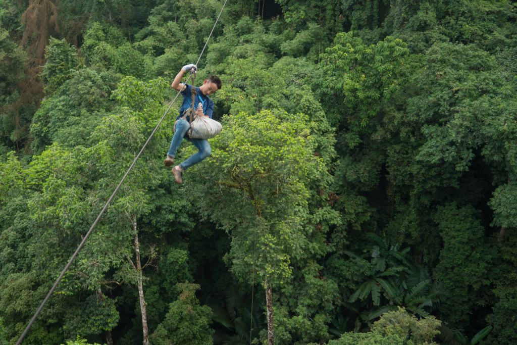 A man ziplining in a forest in Laos.