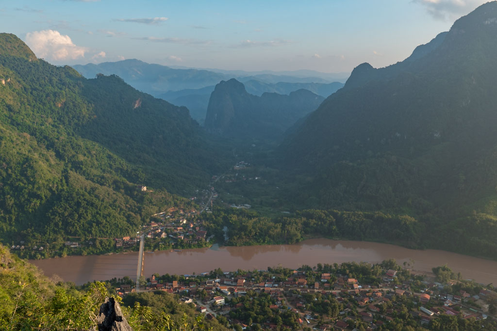 An aerial view of a town with river and surrounded by mountains in Laos.