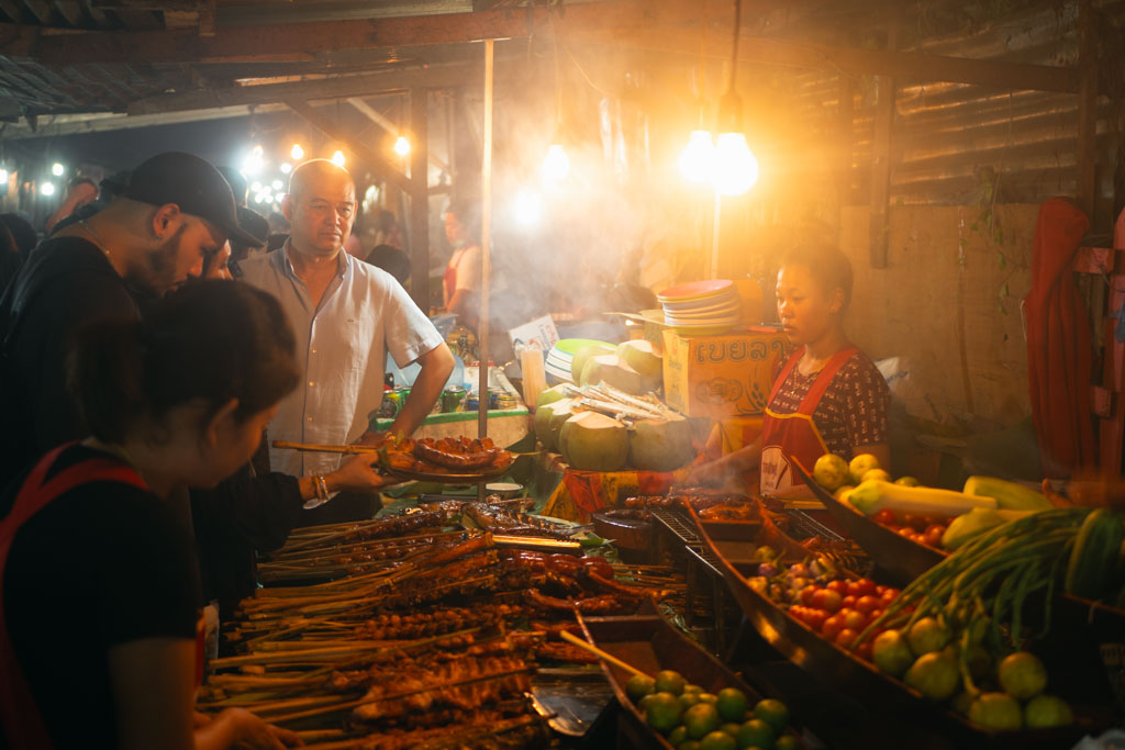 People selling and buying food at a food market in Laos.