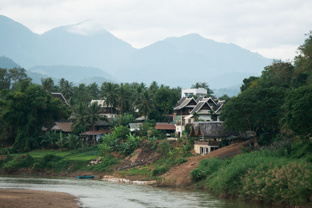 Houses by a river surrounded by mountains in Laos.