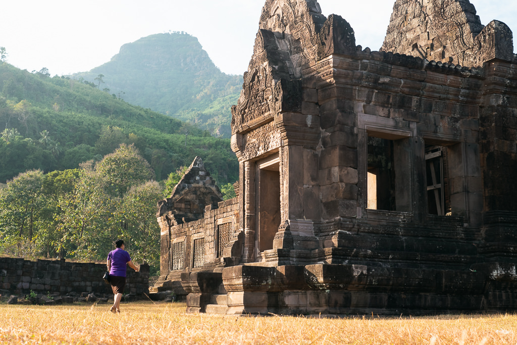 A person walking towards a stone building on a mountain in Laos.