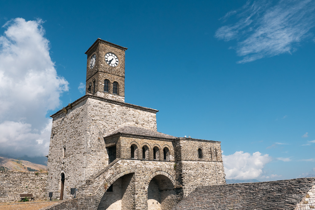 Gjirokaster Castle with a clock tower; blue sky and white clouds in the background.
