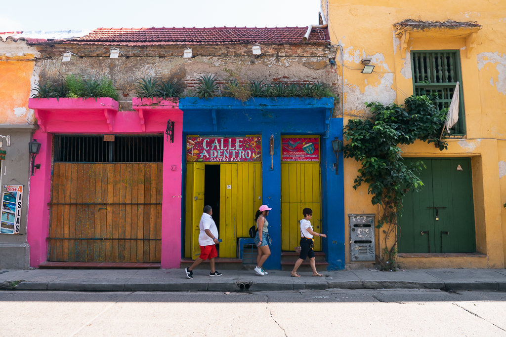 Three people walking on the sidewalk of a road