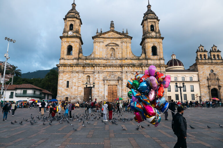 People walking and birds in front of a church.