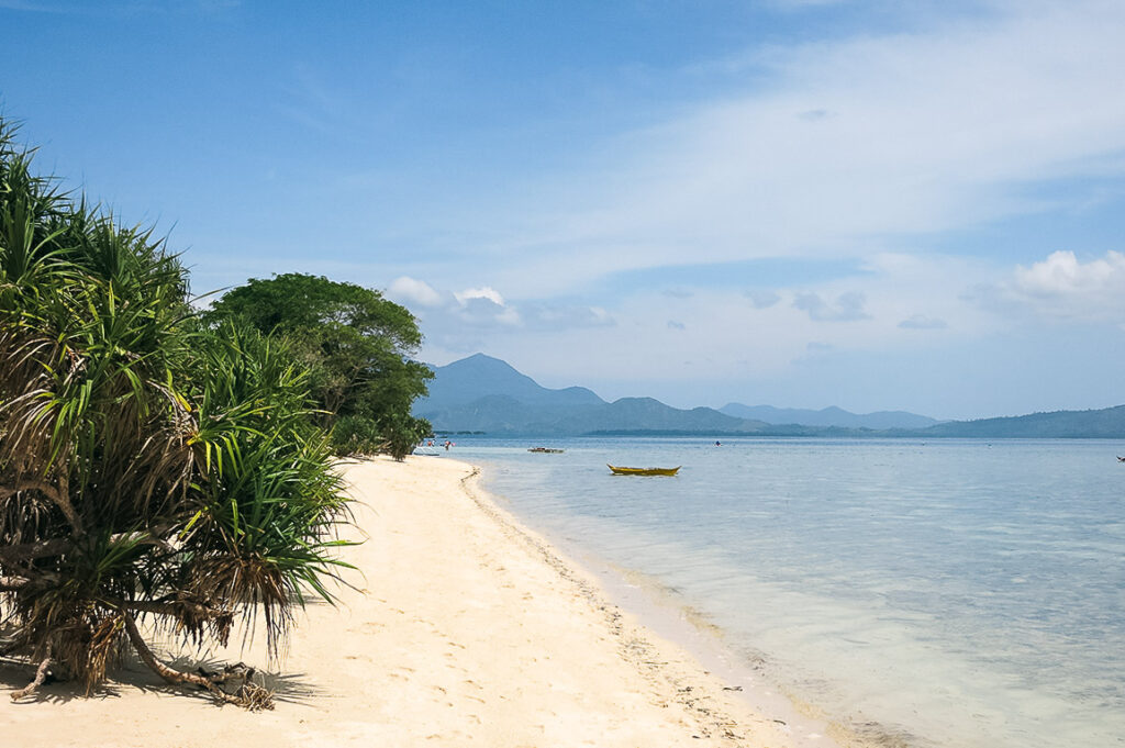 Tropical beach in Honda Bay, Palawan lined with lush trees