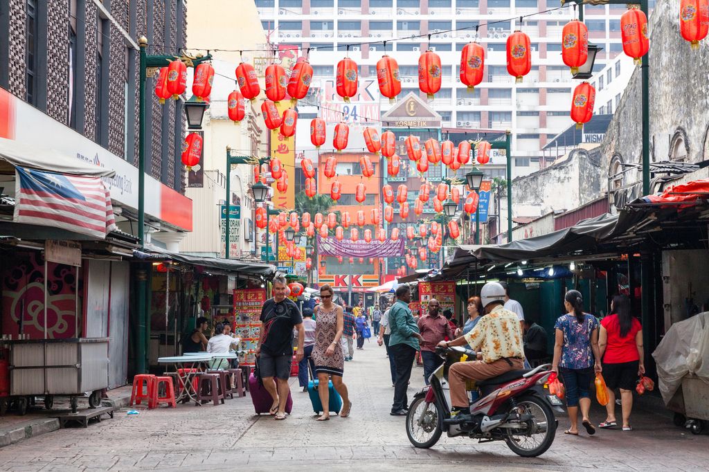 People walking and motorcycle passing on Petaling Street in Chinatown, Kuala Lumpur, Malaysia.