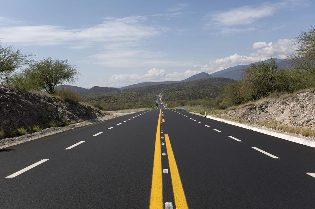 An empty road in Mexico with mountains in the background.