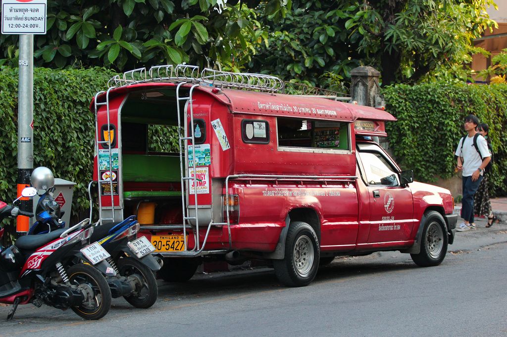 A red Songthaew passenger vehicle in Thailand.