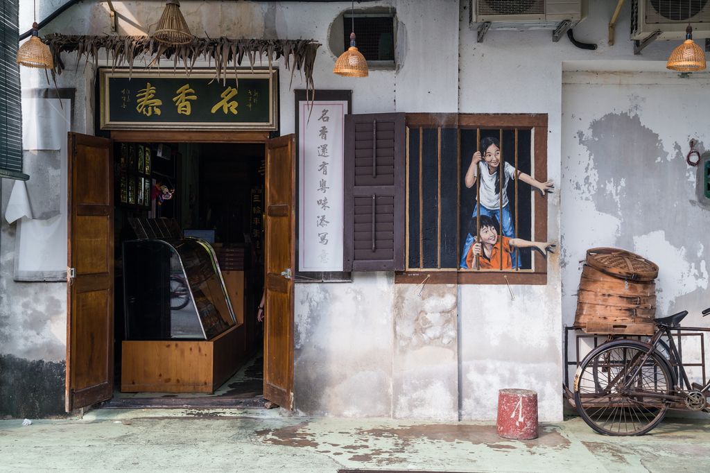 A wall art of two children reaching out from a window in Georgetown, Malaysia