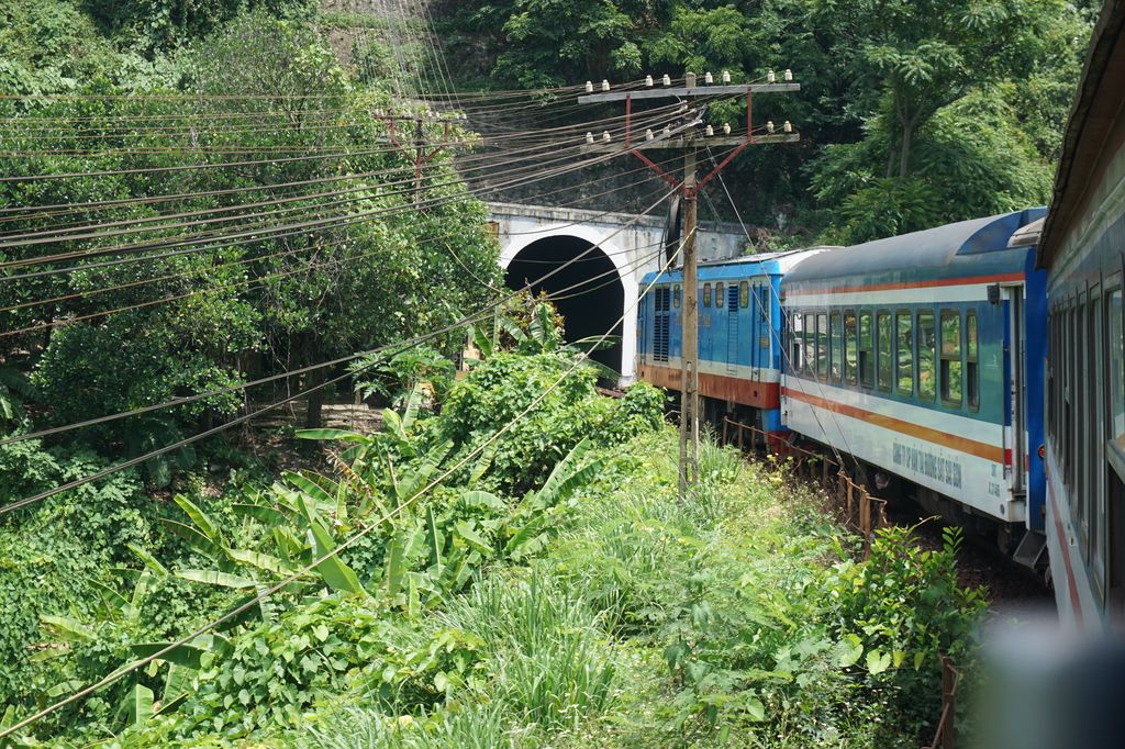 Trees, electric lines, and a train that's going in a tunnel in Hue, Vietnam.