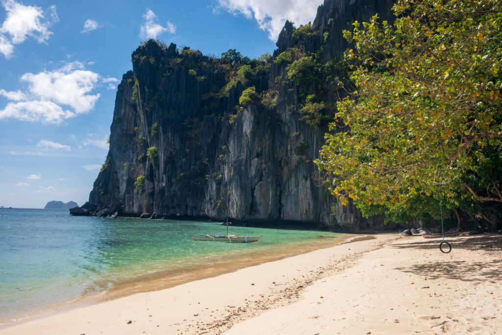 A tropical beach framed by dramatic limestone cliffs in Palawan