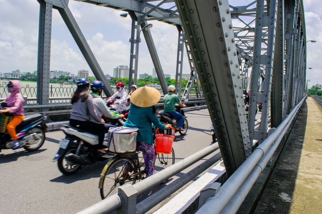 People riding bikes and motorcycles on Truong Tien Bridge in Hue, Vietnam.
