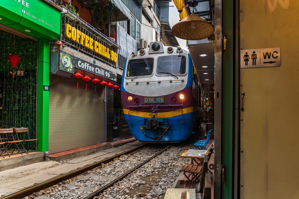 A train in Vietnam passing through a narrow alley trail way.