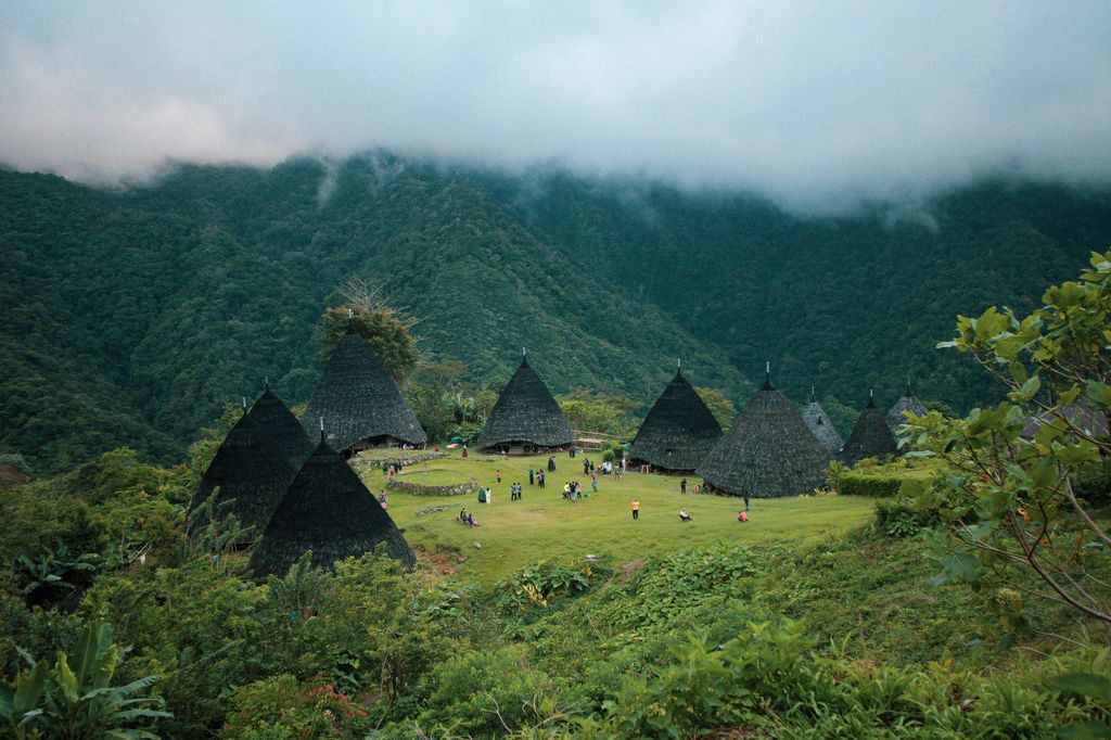 A village with huts and people on a cloudy day in the mountains in Flores, Indonesia.