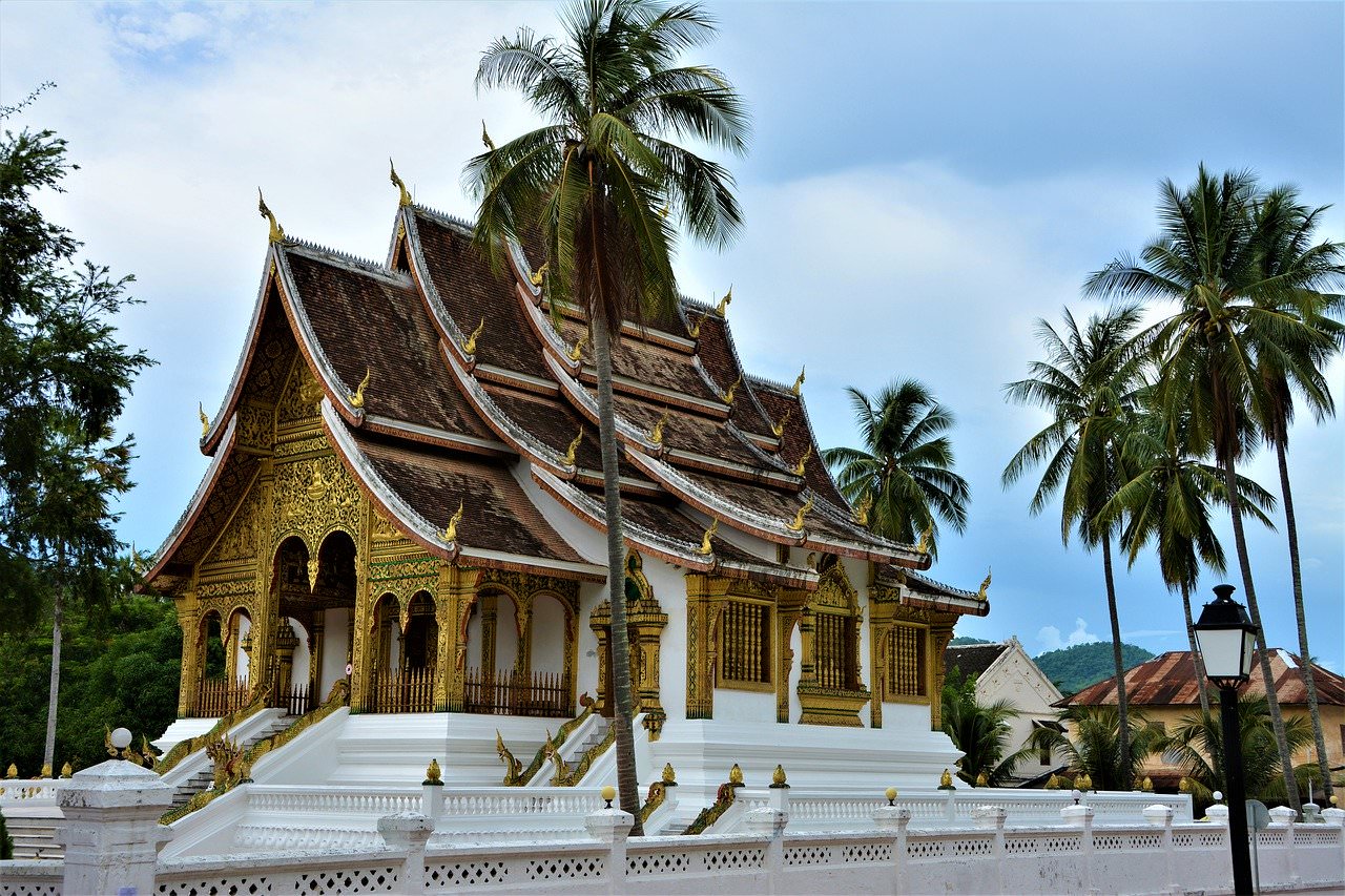 A temple in Luang Prabang, Laos surrounded by palm trees.