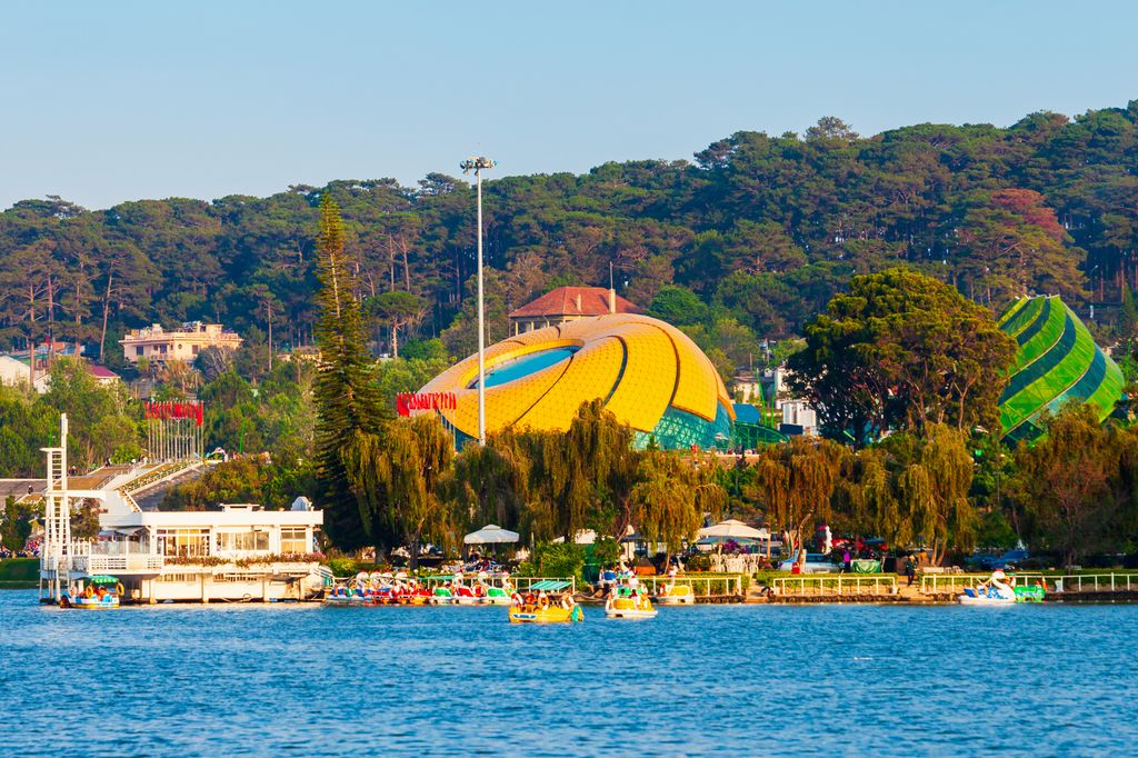 Xuan Huong Lake in Dalat, Vietnam surrounded by mountains, trees, colorful boats, and some park installations.